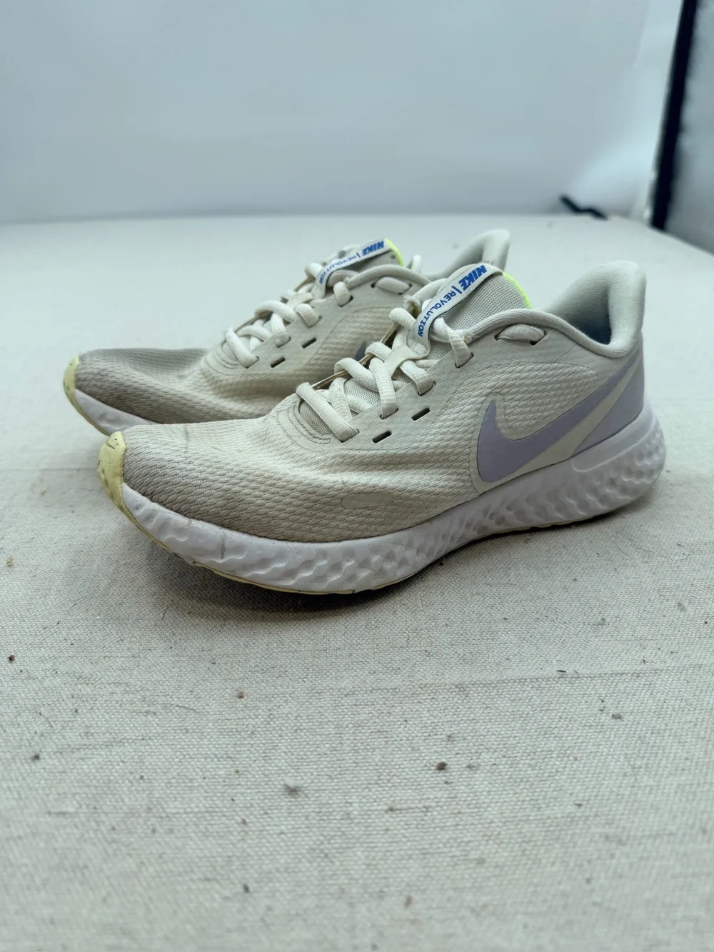 Nike Women’s Revolution Sneakers in Cream with Light Purple Swoosh